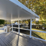 White covered deck with black railing.